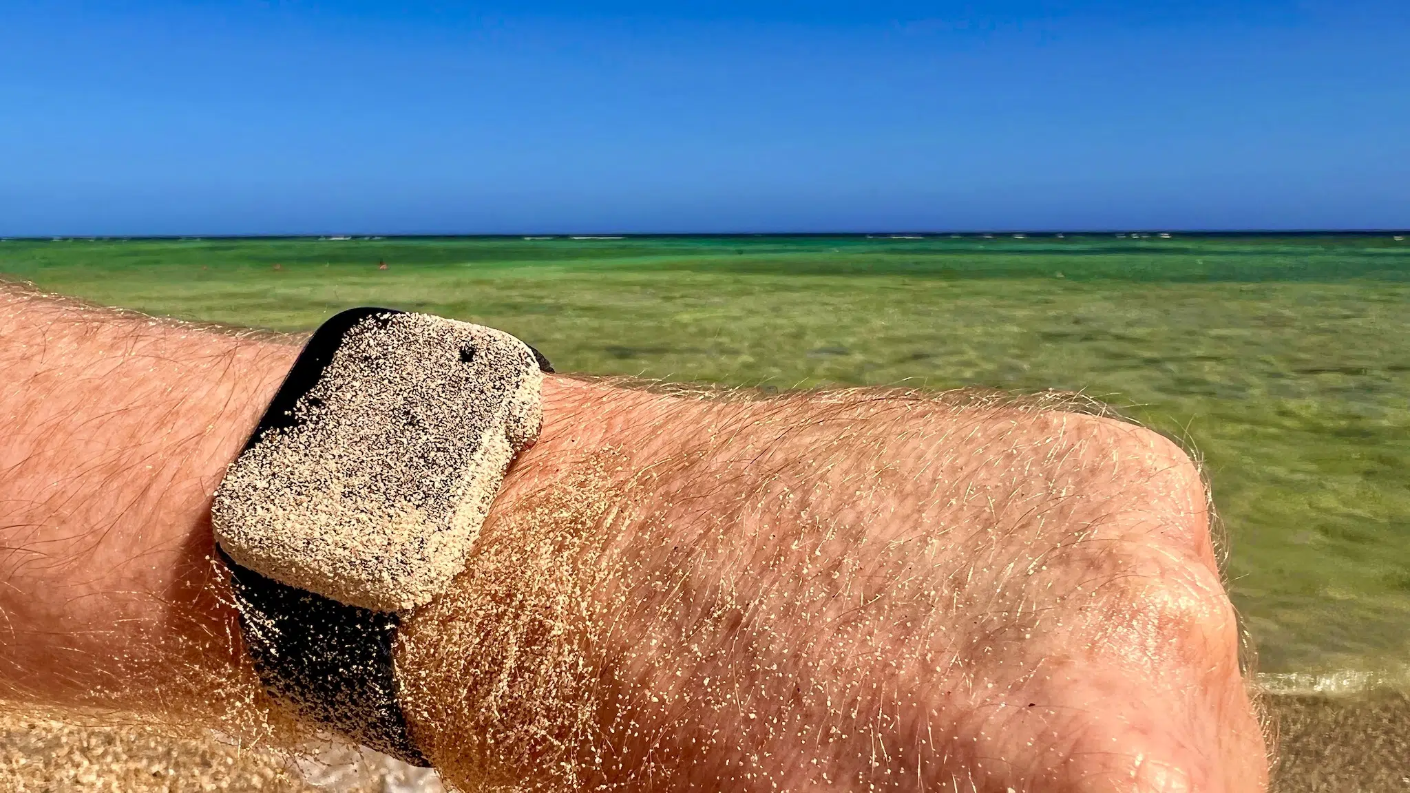 Apple Watch im Salzwasser: Erfahrungen, Pflege und Risiken 4 Apple Watch mit hellem Armband auf einer Hand am sonnigen Strand