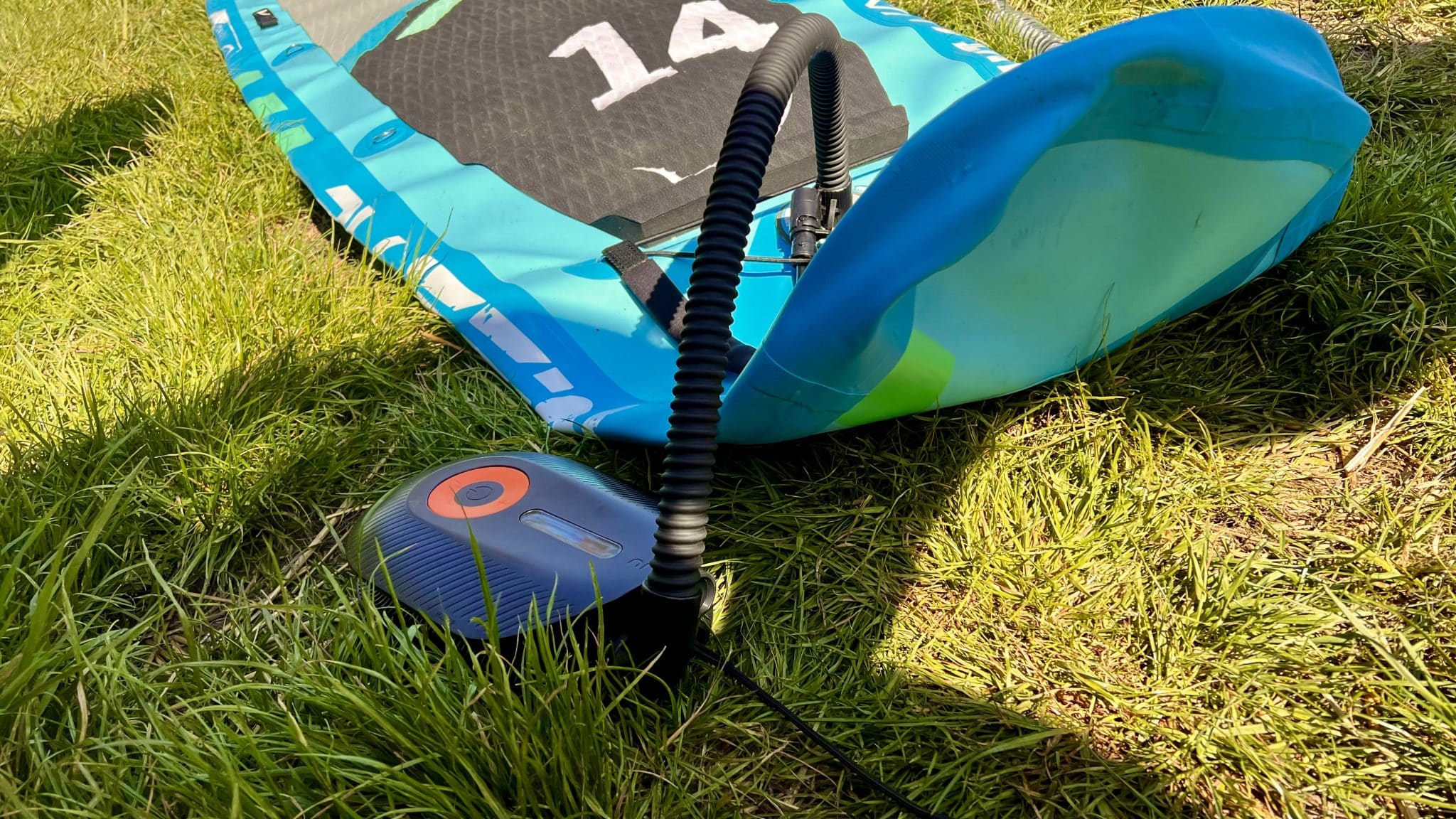 Bluefin Sprint 14 im Test: Erfahrungen mit Tempo, Stabilität und Aufbau 3 Elektrische SUP-Pumpe am Ventil des türkisfarbenen Bluefin Sprint 14 auf einer Wiese
