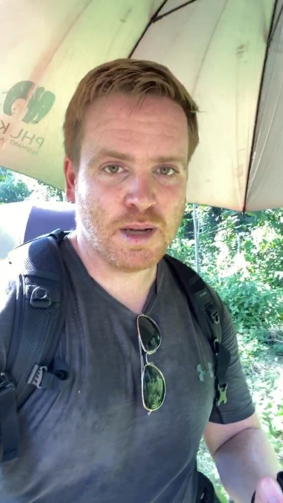 Auf dem Bild sieht man Sascha Tobias Tegtmeyer völlig fertig von der Hitze und durchgeschwitzt mit einem Sonnenschirm, einer Sonnenbrille und seinem Rucksack. 

Ich kann Hitze sonst gut ab, aber im Elephant Sanctuary war es wirklich heftig. Foto: Sascha Tegtmeyer