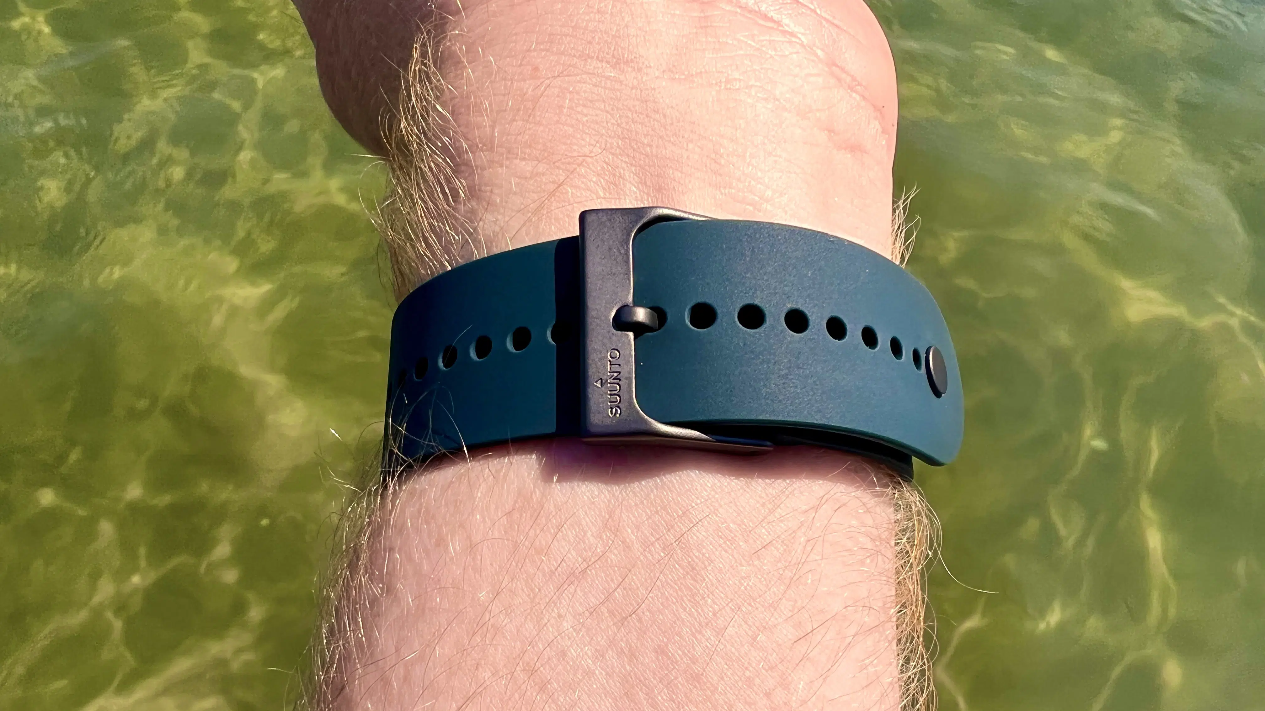 Blaugrünes Silikonarmband einer Suunto 5 Peak am Handgelenk im Wasser