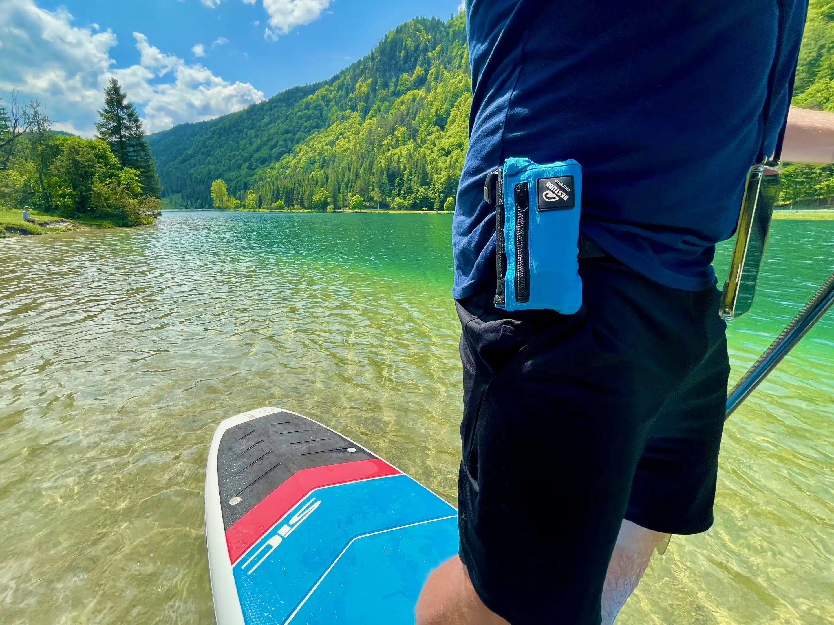 Restube Extreme Test: Erfahrungen nach vielen Jahren 6 Blaues Restube Extreme an Saschas Hüfte neben einem SUP auf einem Bergsee