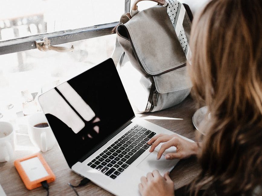 close up photography of woman sitting beside table while using macbook