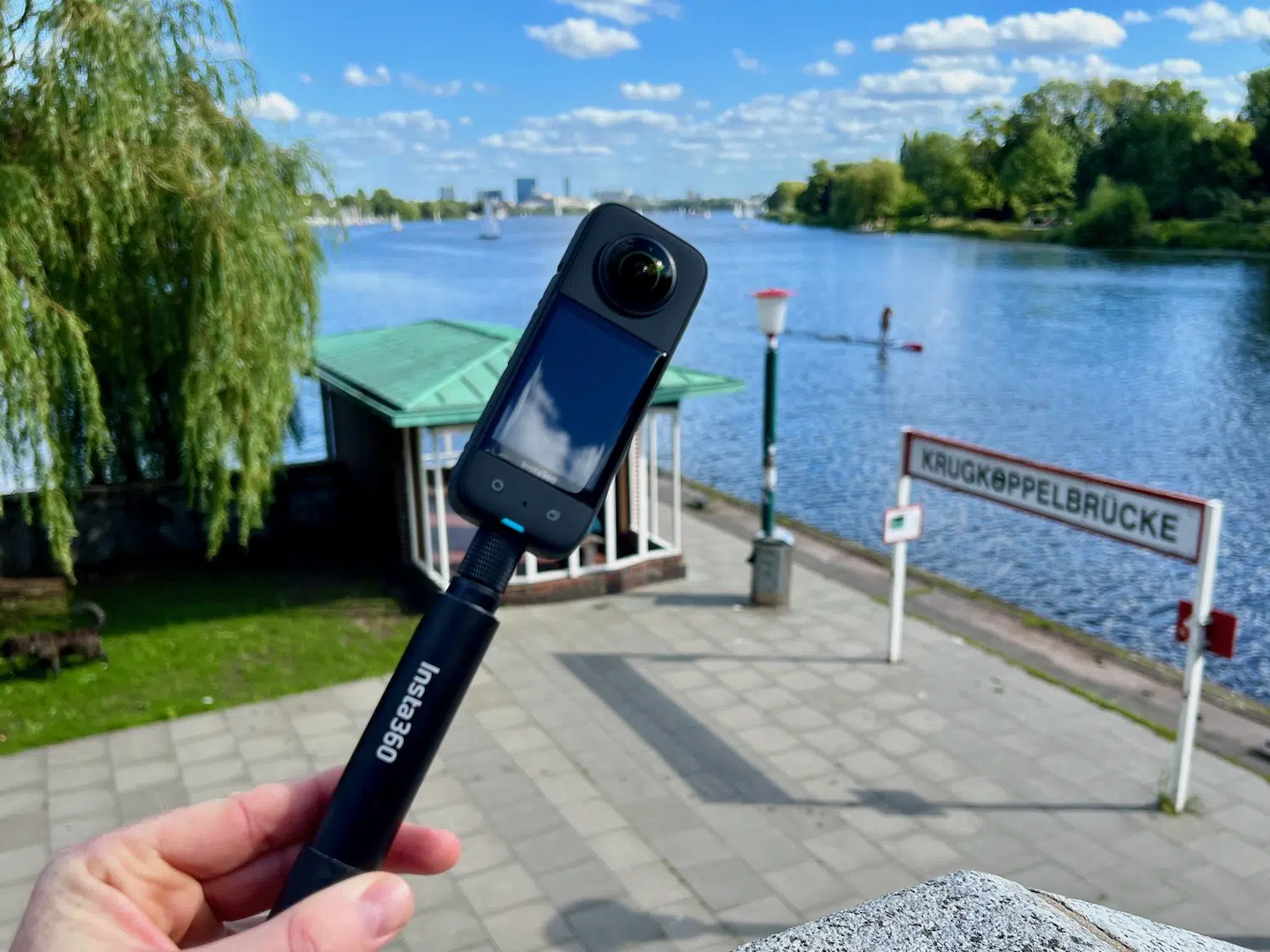 Insta360 X3 Test & Erfahrungen – lohnt sich die 360-Grad-Kamera noch? 4 Insta360 X3 auf einem Selfiestick in der Hand vor einem See