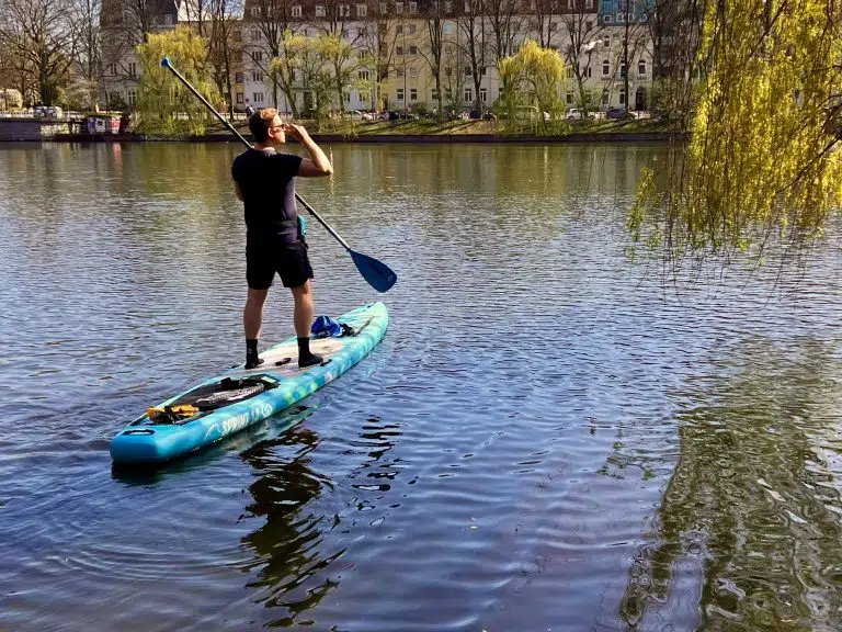 Hamburg – Hafen, Alster & persönliche Tipps 10 Paddler auf einem blauen SUP vor grünen Uferbäumen und Hamburger Wohnhäusern