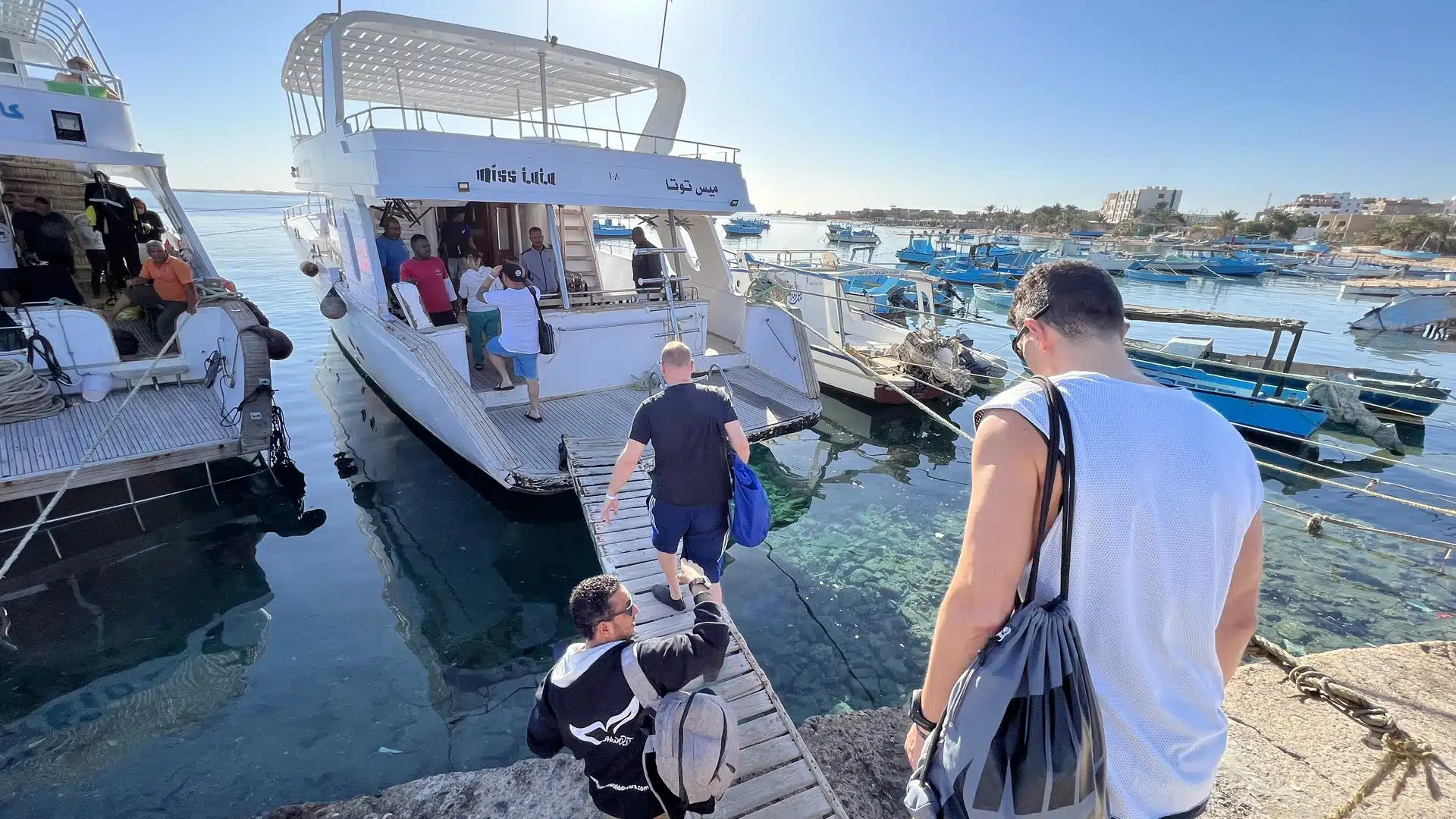 RESTUBE COAST 25 L Test & Erfahrungen – wie gut ist der Rucksack? 8 Taucher gehen über einen schmalen Steg zu einem Tauchboot