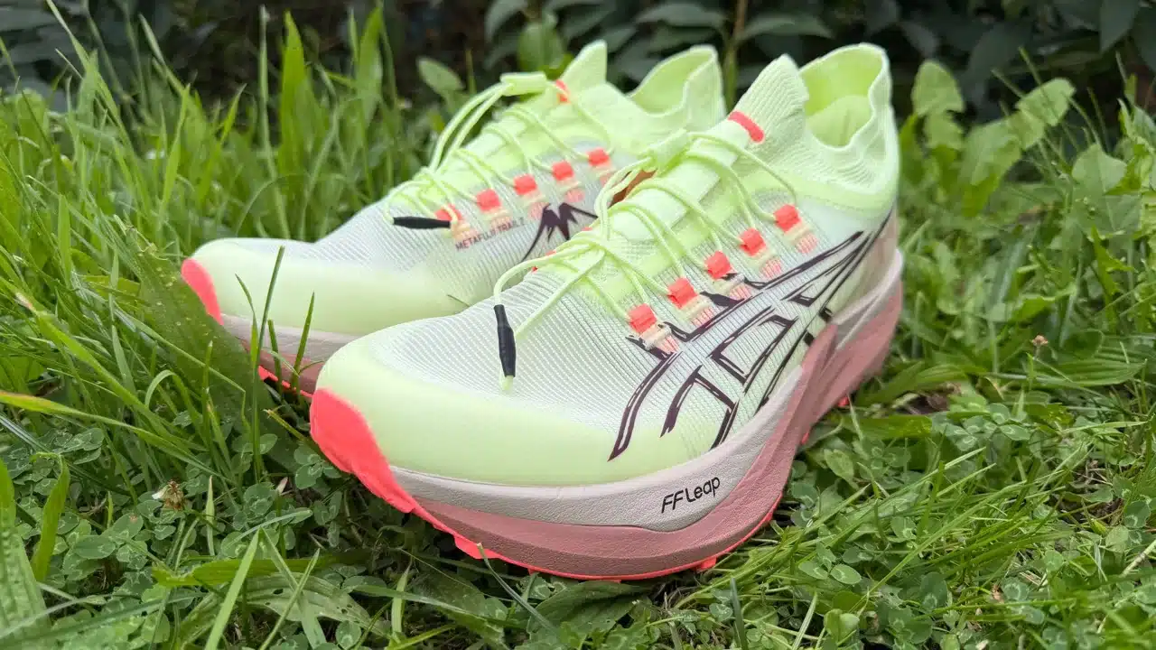 Reisemagazin – Geschichten, Planung, Outdoor und Technik 13 Zwei neue Asics Metafuji Trail 2 in Neon-Gelb und Rosa stehen schräg im Gras.