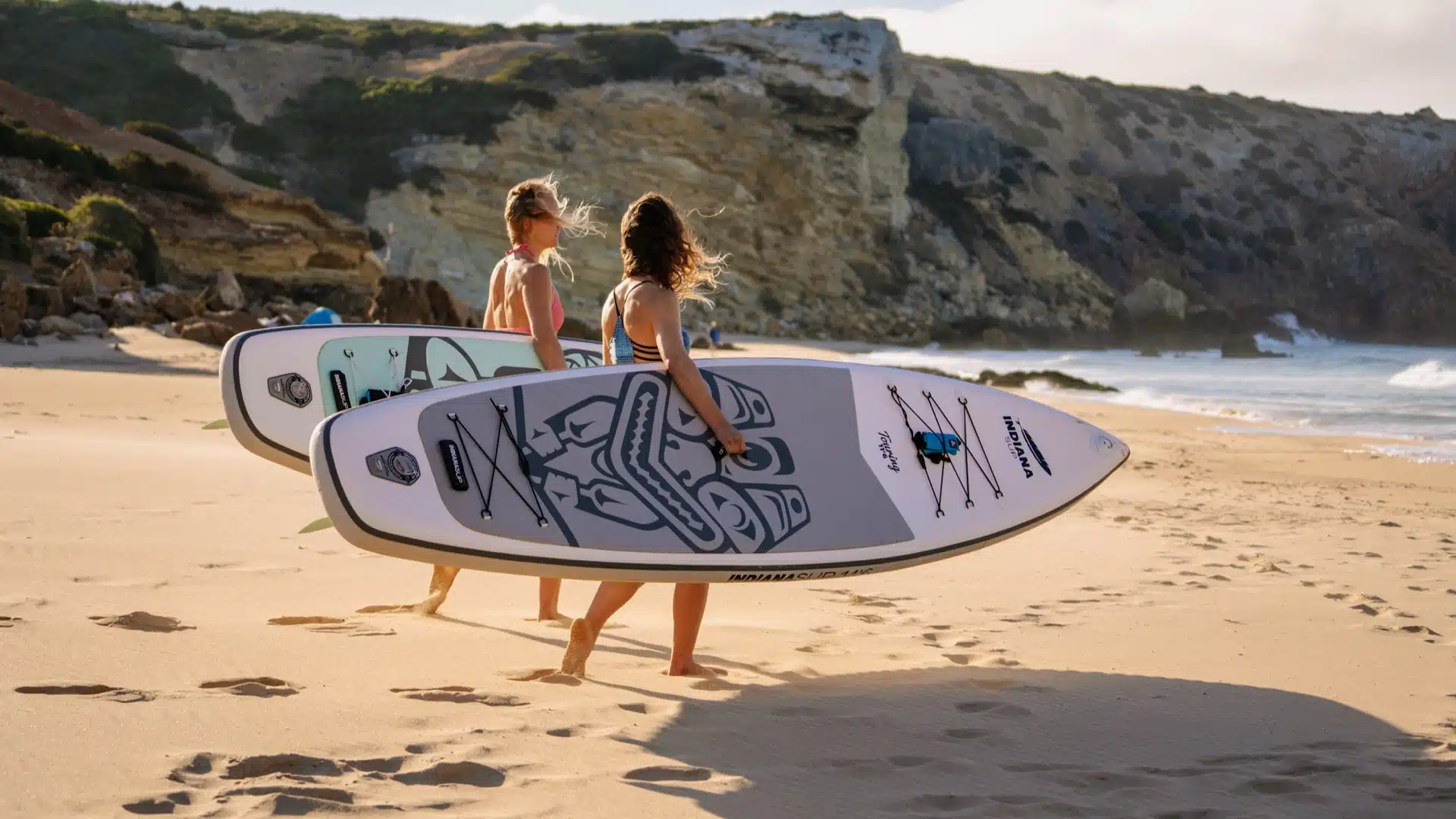RESTUBE COAST 25 L Test & Erfahrungen – wie gut ist der Rucksack? 11 Zwei Stand-up-Paddlerinnen tragen ihre SUP-Boards am Strand