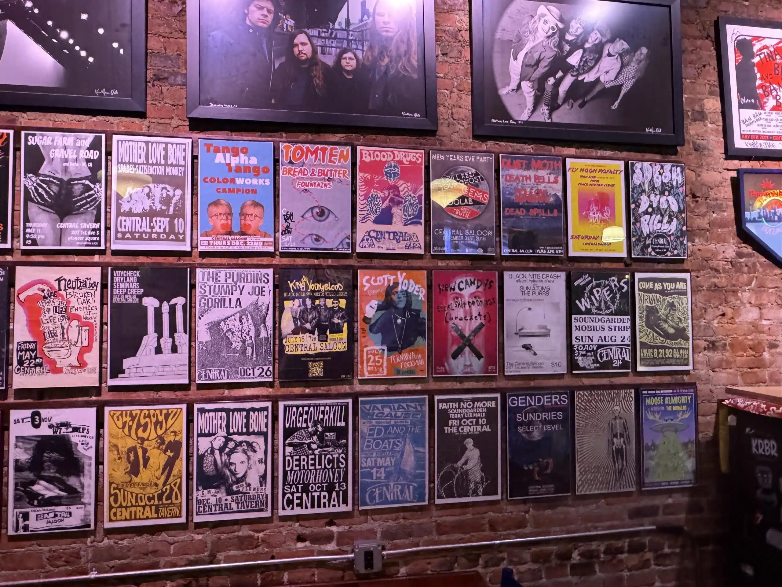 Seattle für Grunge-Fans: Gitarrenläden, Clubs und Nirvana-Spuren 2 Konzertplakate und gerahmte Bandfotos an einer Backsteinwand im Central Saloon