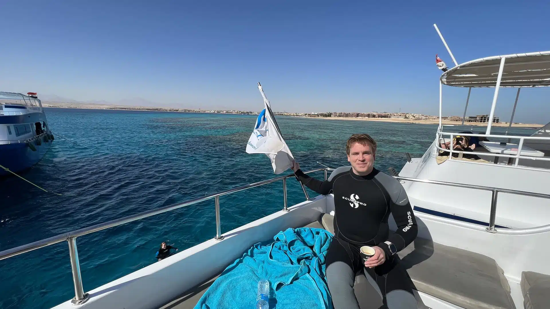 RESTUBE COAST 25 L Test & Erfahrungen – wie gut ist der Rucksack? 9 Sascha sitzt im Neoprenanzug auf einem Tauchboot am Meer