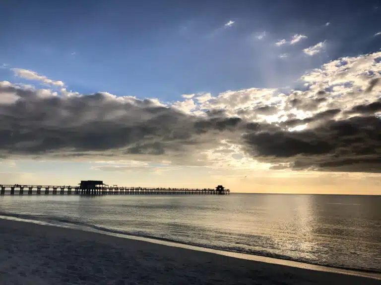 Strand und langer Naples Pier unter Wolken im Abendlicht
