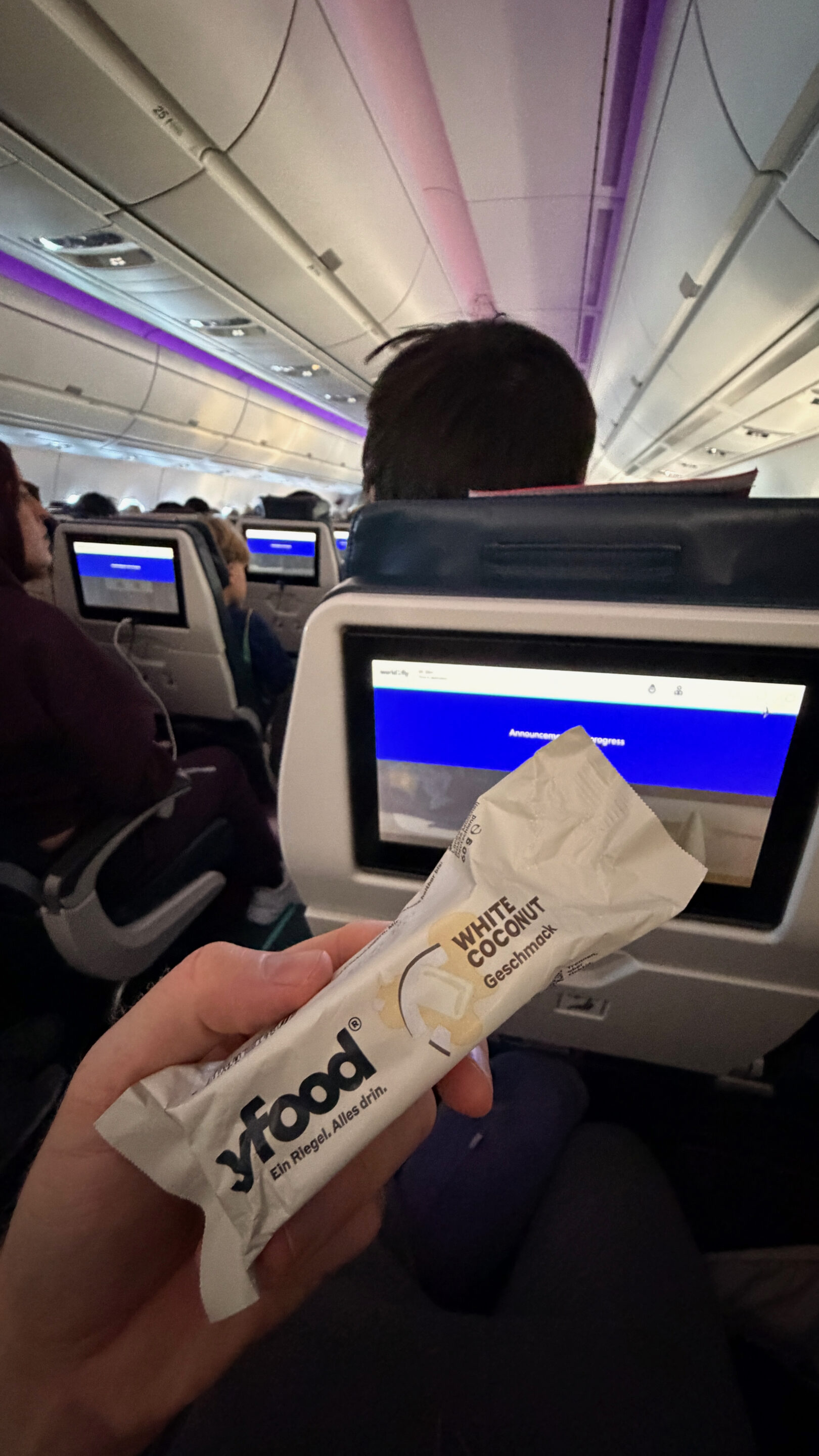 Mein erster Flug im Airbus A350-900: Warum mich das Flugzeug begeistert 10 Mitgebrachter Snack vor dem Sitzbildschirm in der violett beleuchteten A350-Kabine