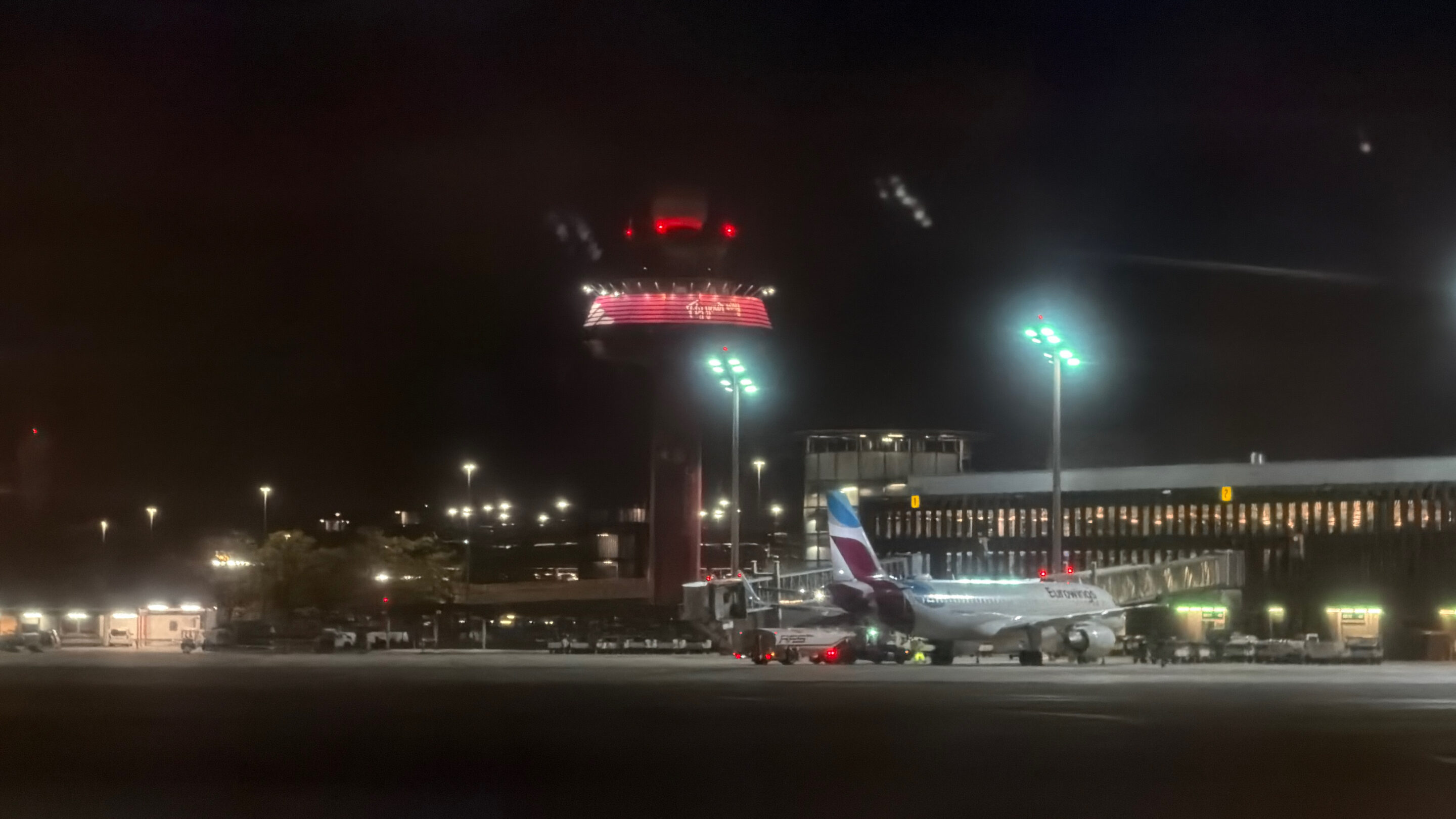 Flughafen Hannover: meine Erfahrungen dort, wo meine erste Flugreise begann 1 Pink beleuchteter Flughafen-Turm hinter einem Flugzeug auf dem Vorfeld